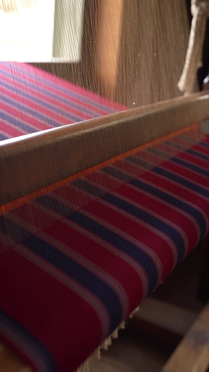 A weaver at a loom, raw silk running through the warp