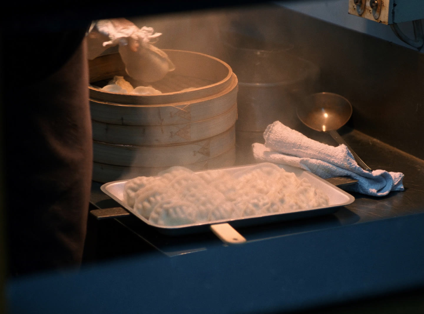 A tray of freshly steamed momo dumplings lifted from a bamboo steamer in a kitchen
