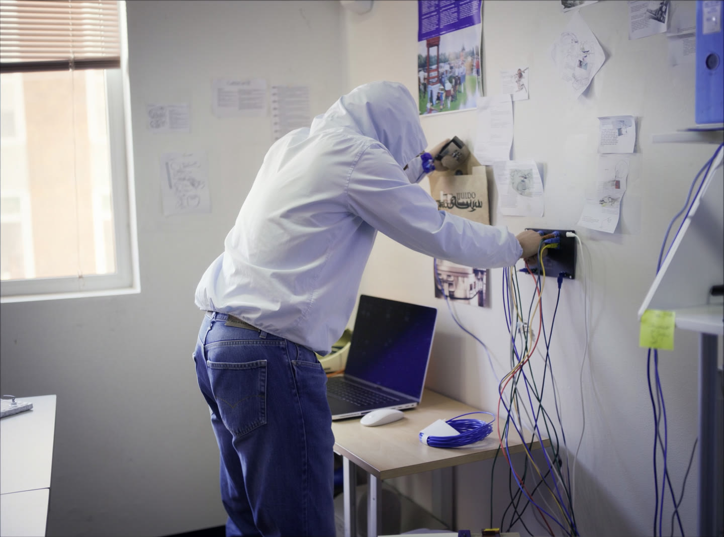 A technician terminating network cables into a wall-mounted patch panel in a small office