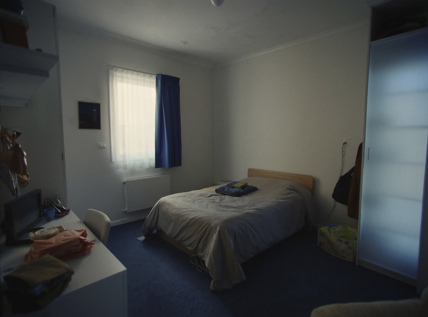 A simple furnished single bedroom in a shared Australian house with a desk and a curtained window