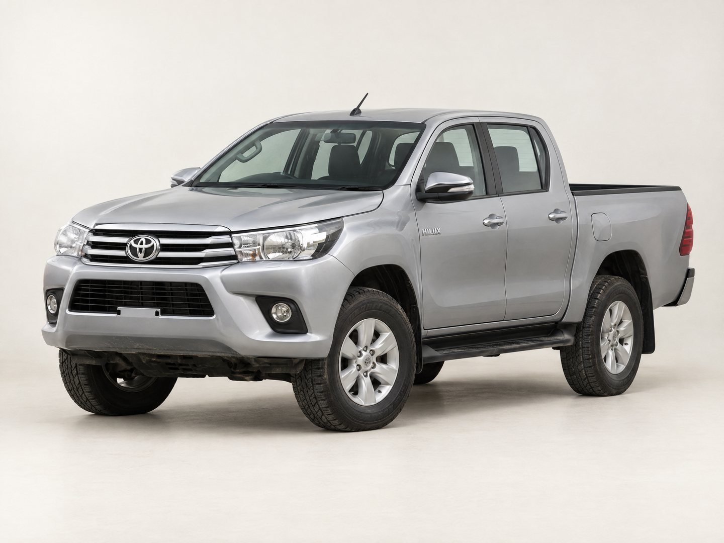A silver double cab pickup truck photographed in a studio against a plain light ground